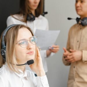 Team of professionals in a call center discussing customer service strategies while wearing headsets.